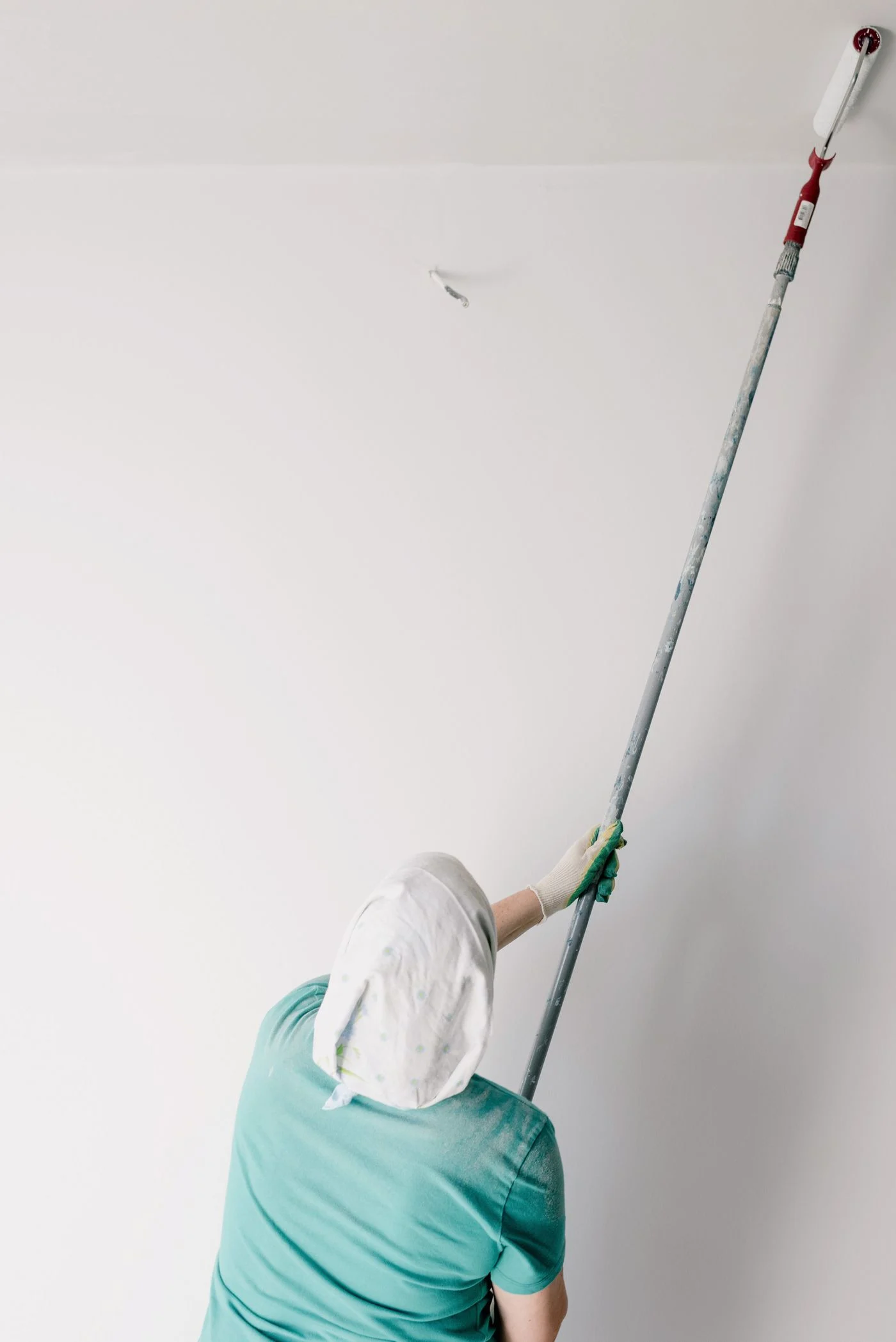 Pintor profesional preparando y pintando techo blanco con protección integral en Granada